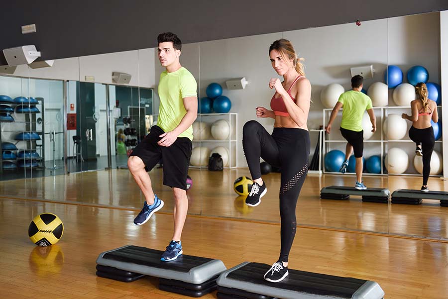 man and women working out doing cardio ontop of equipment